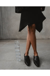 vegan leather loafers, worn against a grey backdrop with glass cups alongside
