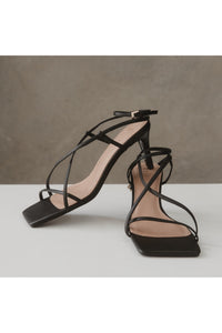 black vegan leather strappy heels by edie collective, the stella multistrap, against stone backdrop